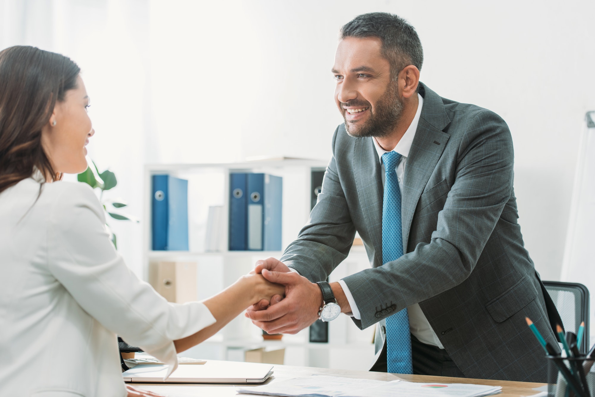 handsome-advisor-in-suit-shaking-hands-with-investor-at-workplace.jpg